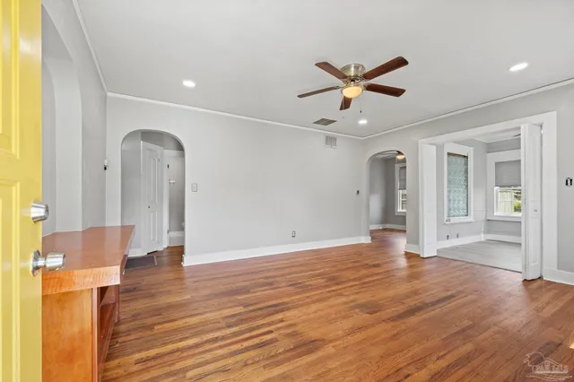 a view of an empty room with window and wooden floor