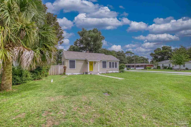 a view of a yard in front of a house with a large tree