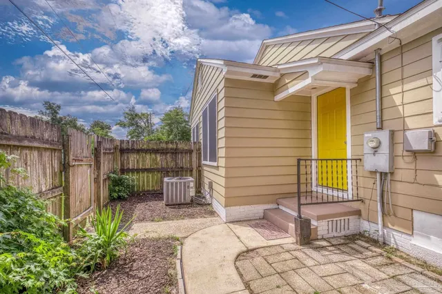 a backyard of a house with table and chairs and a large tree