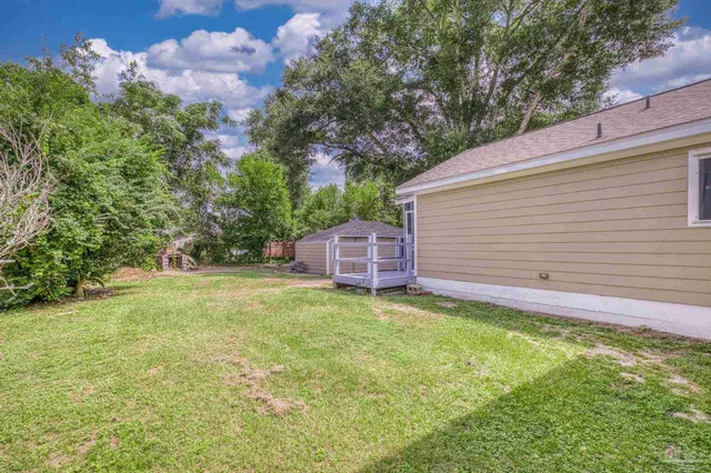 a backyard of a house with table and chairs plants and large tree