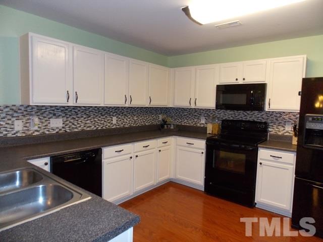 1621 Extine Lane Raleigh, NC 27610 - Photo 7 of 25 a kitchen with granite countertop white cabinets and black appliances