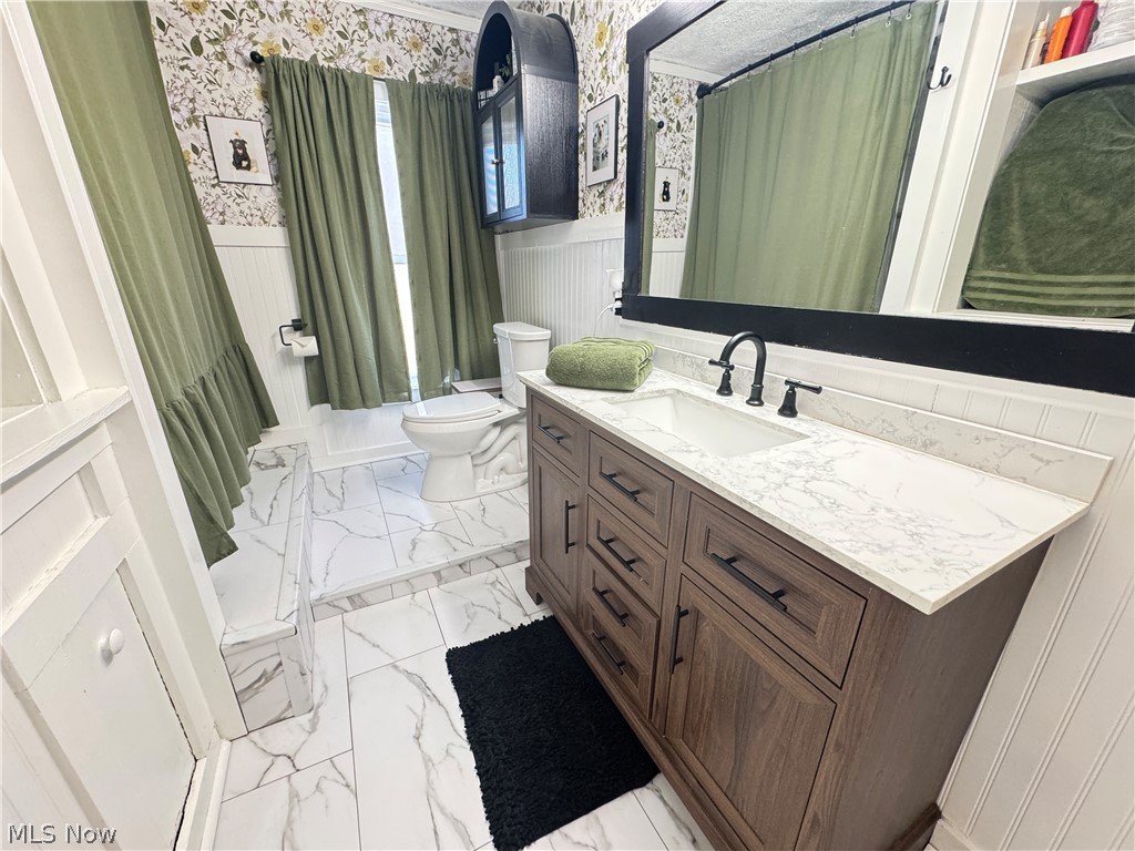 1047 Howell Road East Palestine, OH 44413 - Photo 12 of 20 Bathroom with wainscoting, vanity, wallpapered walls, and light marble finish floors
