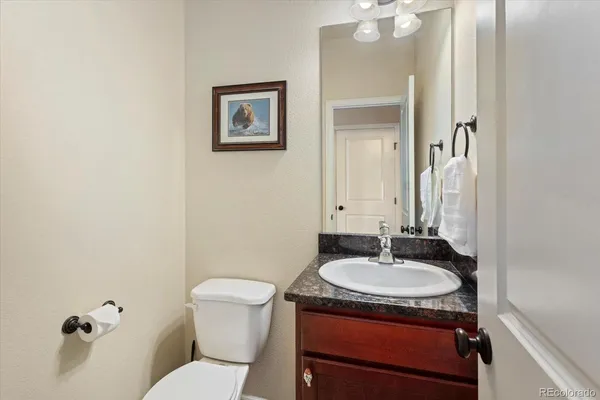 a bathroom with a granite countertop sink toilet and mirror