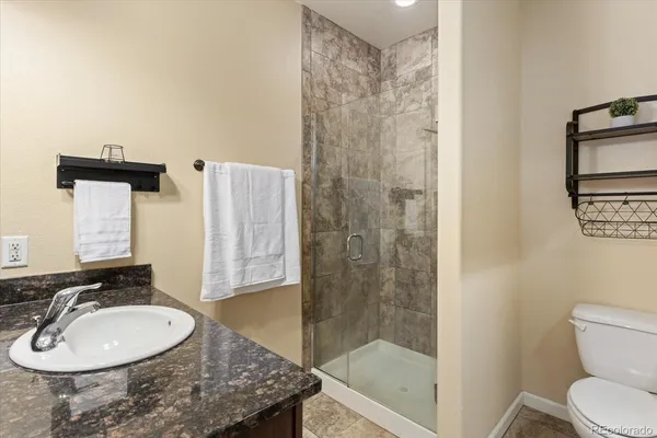 a bathroom with a granite countertop sink a toilet and shower