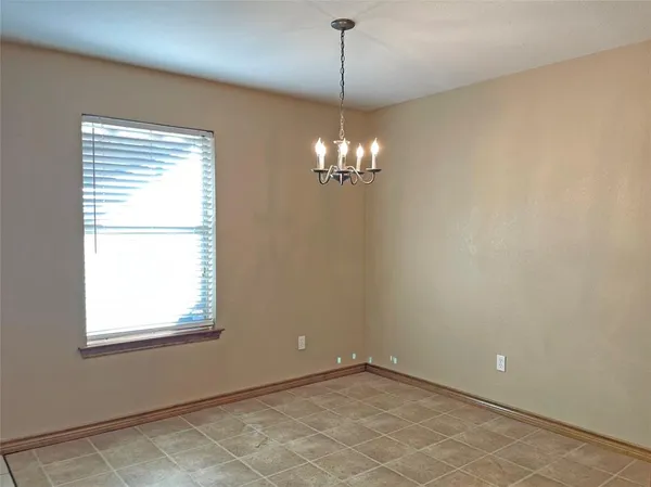 a view of an empty room with window and chandelier fan