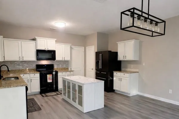 a kitchen with stainless steel appliances a refrigerator a stove a sink cabinets and wooden floor