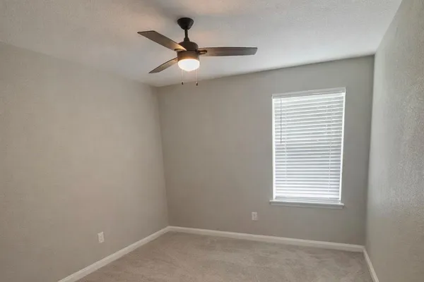 an empty room with a window and a fan