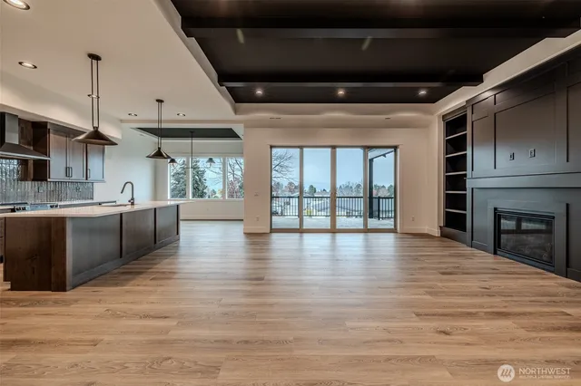 a view of an empty room with wooden floor and a kitchen