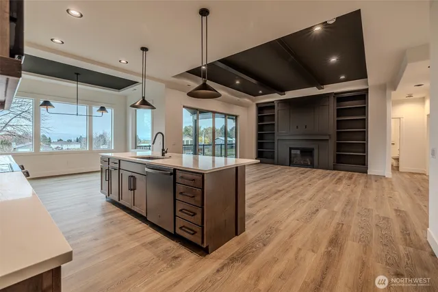 a large kitchen with stainless steel appliances a large counter top a stove and a wooden floors