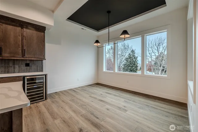 an empty room with wooden floor cabinet and windows