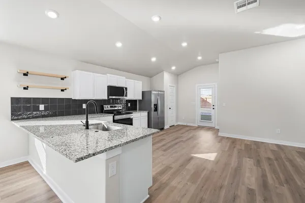 a kitchen with stainless steel appliances granite countertop a sink stove and refrigerator