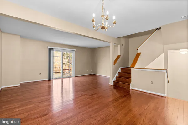 a view of an empty room with wooden floor and window