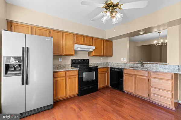 a kitchen with stainless steel appliances granite countertop a refrigerator a sink dishwasher a stove with white cabinets and wooden floor