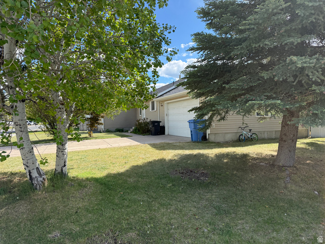 44 Wapiti Loop Hyrum, UT 84319 - Photo 2 of 18 Front exterior featuring a two-car garage with a white door, light-colored siding, and a concrete driveway