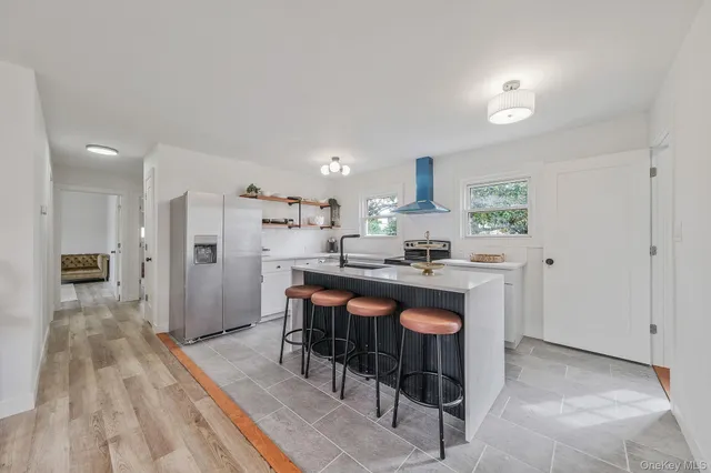 a kitchen with stainless steel appliances granite countertop a refrigerator a sink dishwasher and a stove with wooden floor