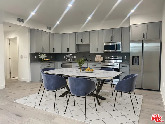 a kitchen with stainless steel appliances granite countertop a refrigerator a stove a sink and white cabinets