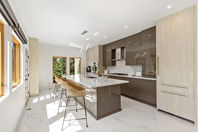 a large white kitchen with a sink and dishwasher a stove top oven with wooden floor