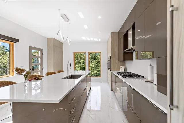 a large kitchen with kitchen island a large counter top space a sink a stove and a window
