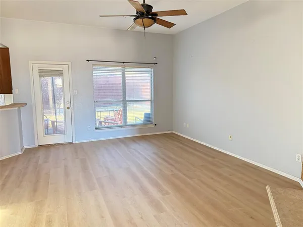 an empty room with wooden floor fan and windows