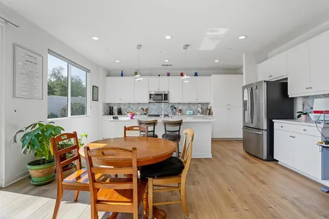 a kitchen with a dining table chairs refrigerator and microwave