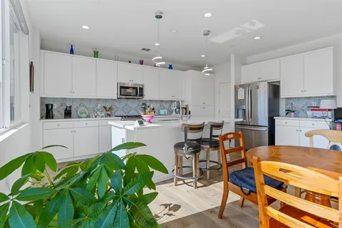 a kitchen with stainless steel appliances kitchen island granite countertop a refrigerator and a dining table