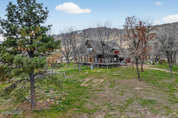 a view of a house with a big yard and large trees