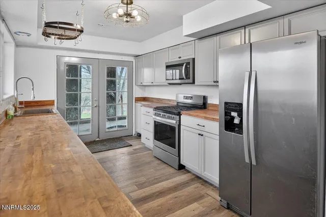 a kitchen with stainless steel appliances granite countertop a refrigerator a stove and a sink with wooden floor