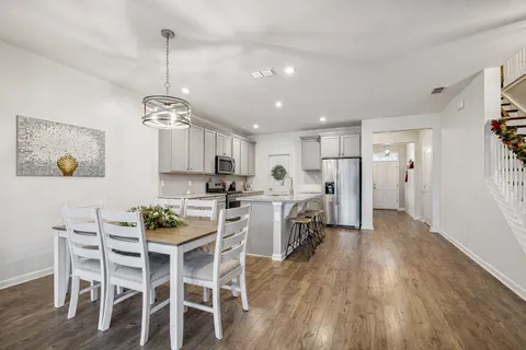 a view of a dining room and livingroom with furniture wooden floor a chandelier