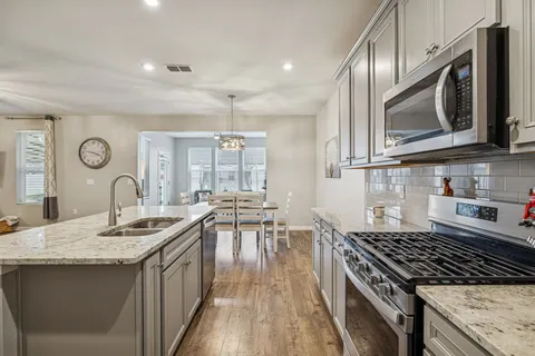 a kitchen with granite countertop a sink stove and cabinets