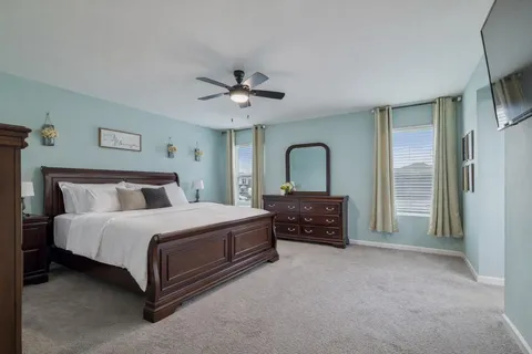 a spacious bedroom with a bed a dresser and a large window