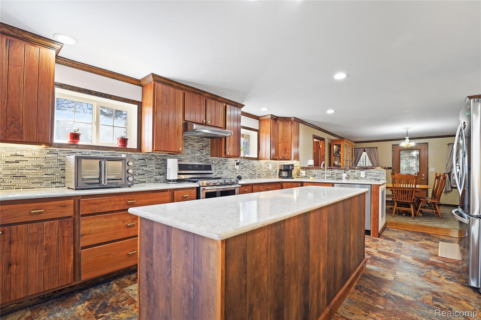 7149-7163 Burpee Road Grand Blanc, MI 48439 - Photo 54 of 72 Kitchen featuring crown molding, plenty of natural light, stone finish flooring, decorative backsplash, and stainless steel appliances