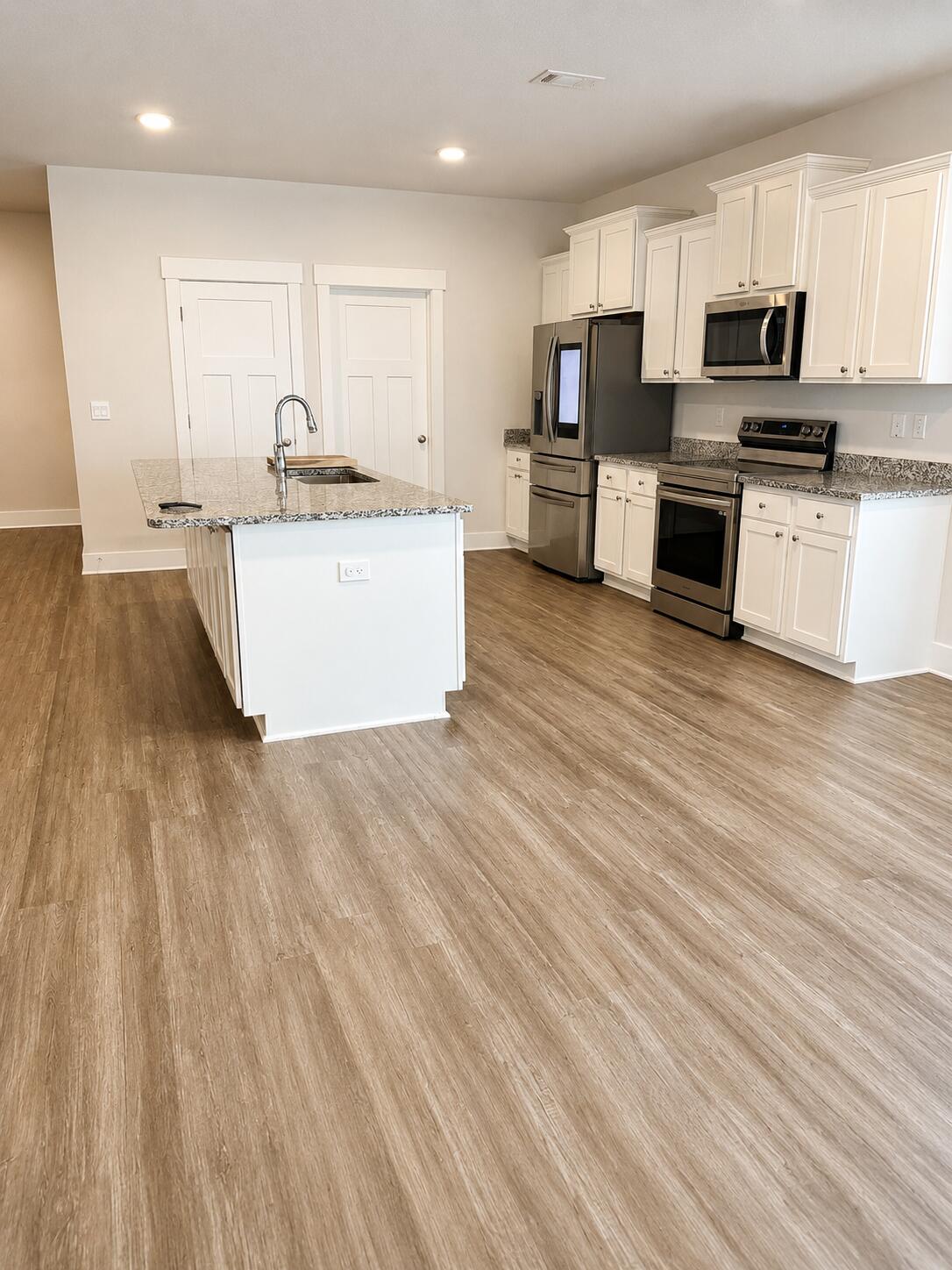 734 Quintana Street Crestview, FL 32539 - Photo 3 of 16 a large kitchen with stainless steel appliances kitchen island granite countertop a sink dishwasher a stove top oven a refrigerator with island and cabinets