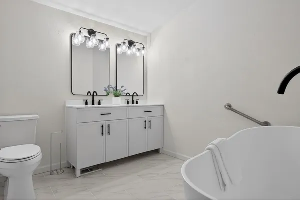 a bathroom with a double vanity sink toilet and mirror
