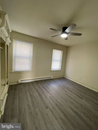 an empty room with wooden floor chandelier fan and windows