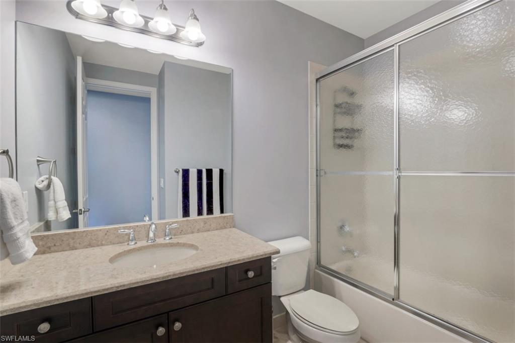 3082 Hudson Terrace Naples, FL 34119 - Photo 30 of 35 a bathroom with a granite countertop sink toilet a mirror a vanity and shower