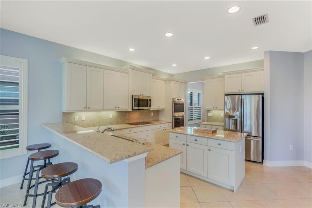3082 Hudson Terrace Naples, FL 34119 - Photo 9 of 35 a kitchen with a sink a stove and chairs
