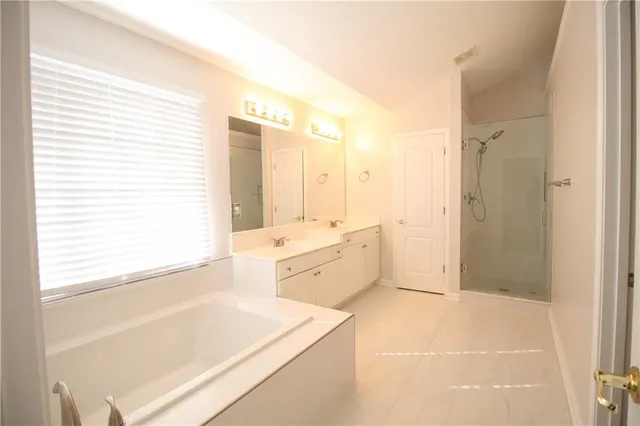 a large bathroom with a tub sink shower and mirror