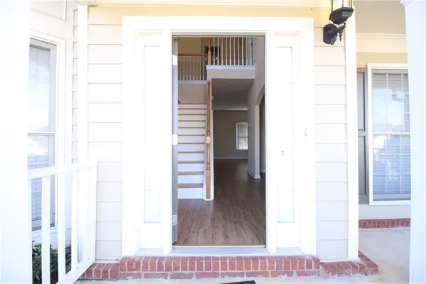 a view of a hallway with wooden floor and a bathroom