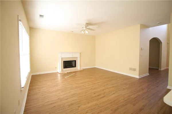a view of an empty room with wooden floor and a fireplace