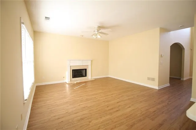a view of an empty room with wooden floor and a fireplace