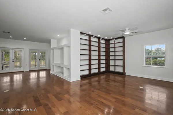 a view of an empty room with a window and wooden floor