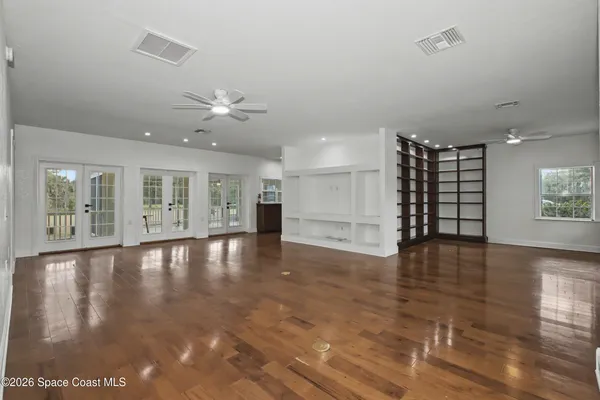 an empty room with wooden floor and windows