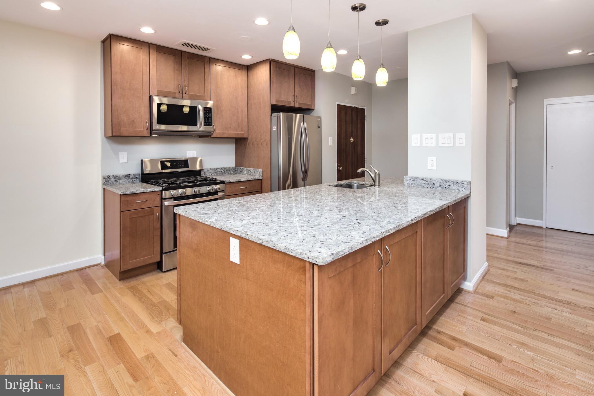 2475 Virginia Avenue Northwest, Unit 103 Washington, DC 20037 - Photo 5 of 16 a kitchen with stainless steel appliances granite countertop a kitchen island a stove a refrigerator and a sink