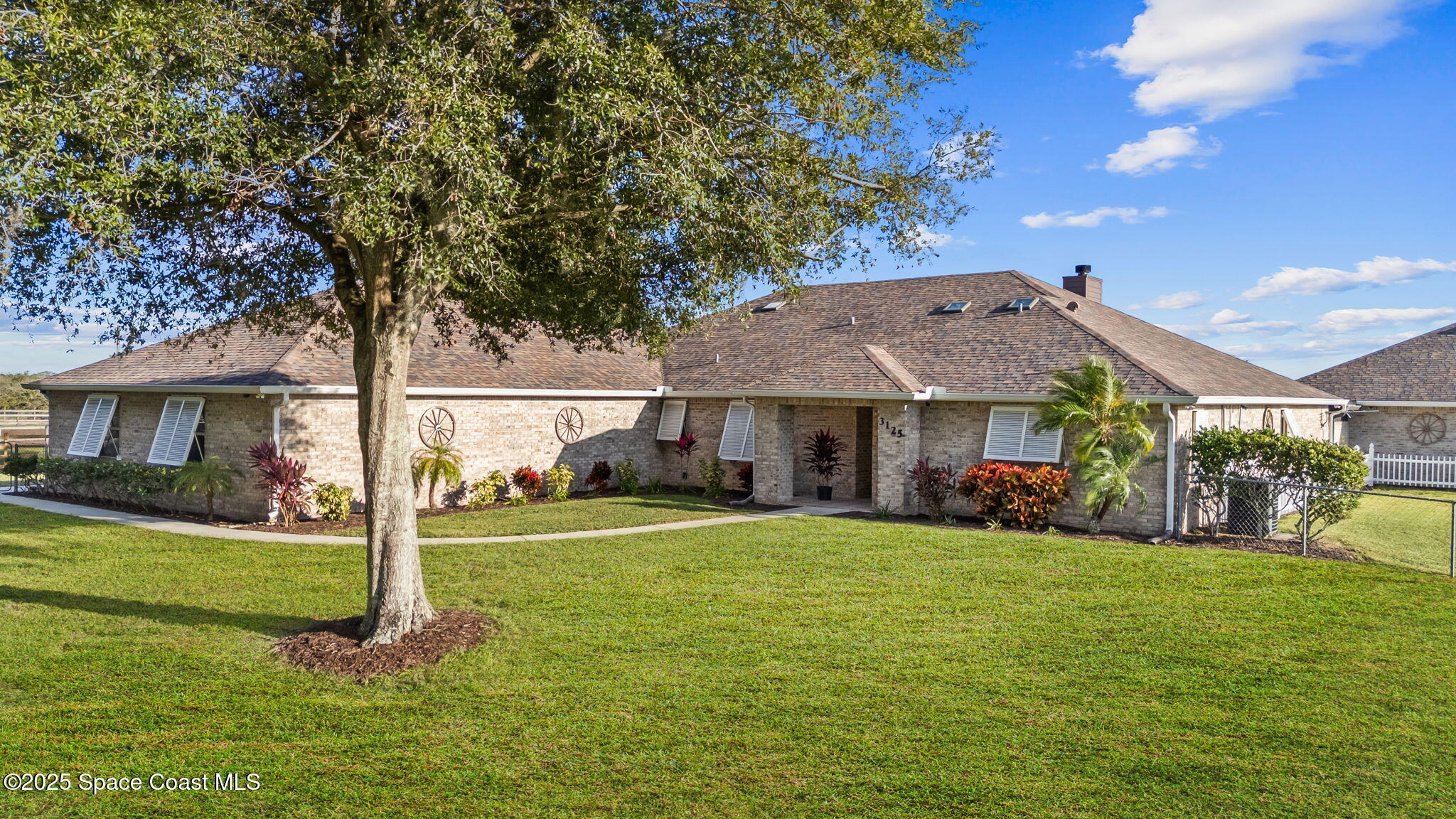 a view of a big house with a big yard and large trees