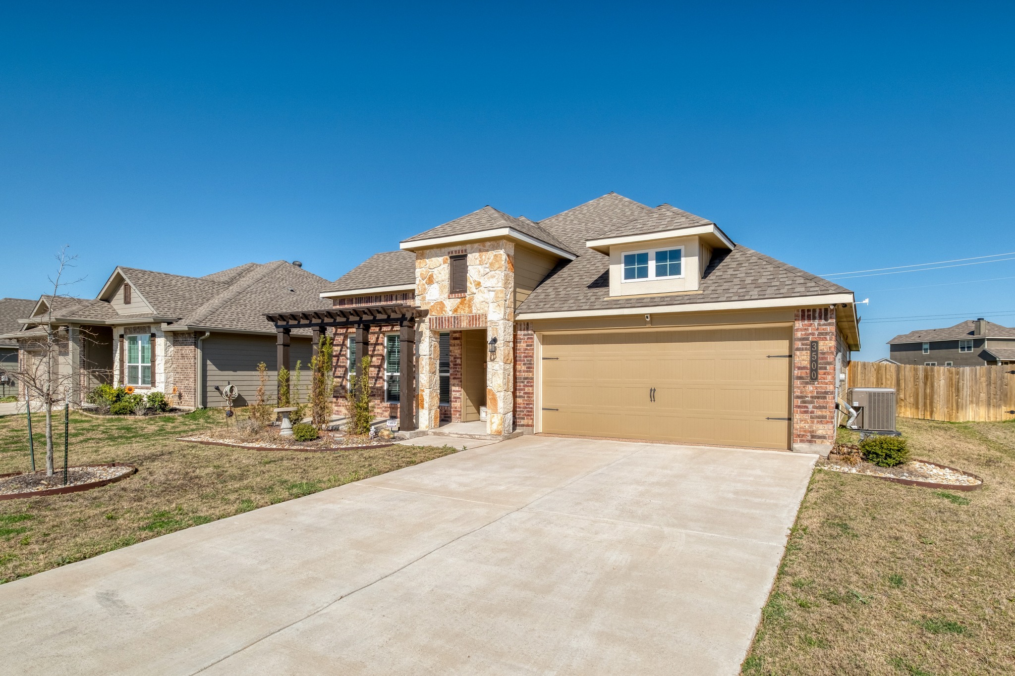 3500 Beutel Road Lorena, TX 76655 - Photo 4 of 27 Prairie-style home with concrete driveway, a pergola, roof with shingles, an attached garage, and stone siding