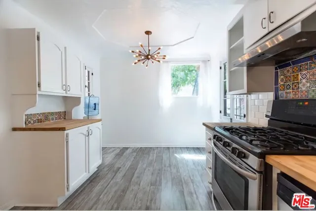 a large kitchen with stainless steel appliances a stove a sink dishwasher and a refrigerator with wooden floor