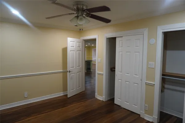 an empty room with wooden floor closet and windows