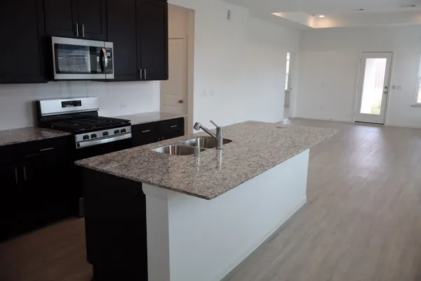 a kitchen with stainless steel appliances granite countertop a sink wooden cabinets and a granite counter tops
