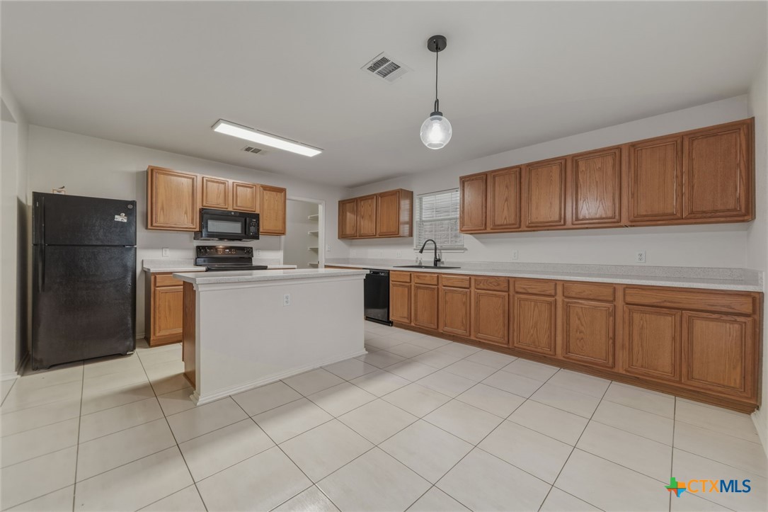 109 Comal Cove Elgin, TX 78621 - Photo 10 of 34 a kitchen with stainless steel appliances granite countertop a refrigerator sink and cabinets