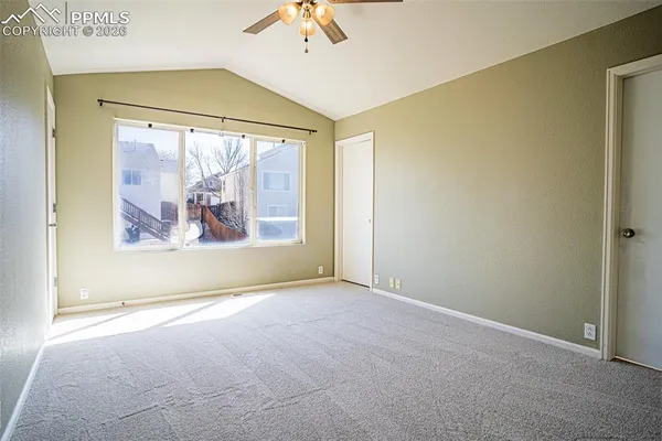 an empty room with windows and chandelier fan